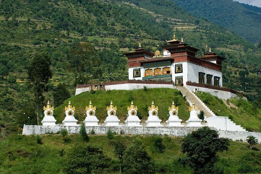 A white and red building with golden spires on a hill, surrounded by greenery. 5