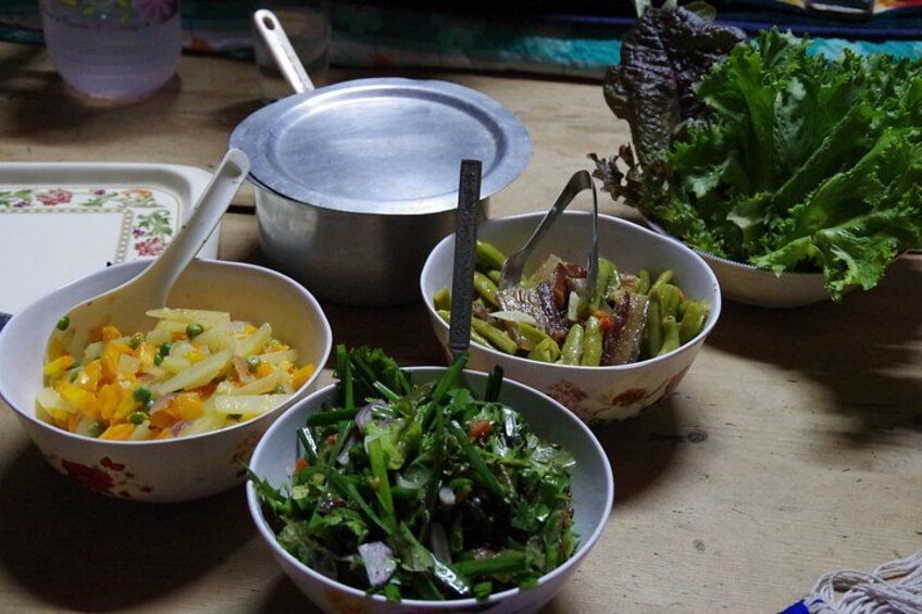 Three bowls of food on a table with a pot and a spoon. 4