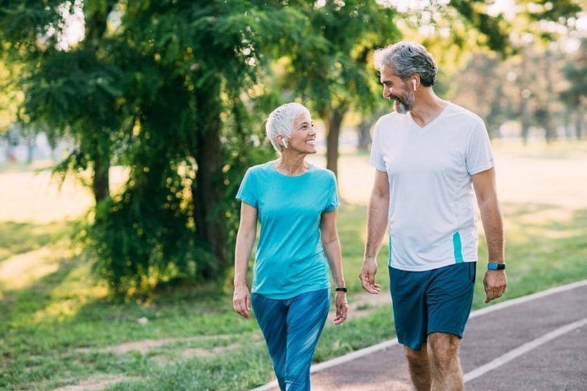 Two people walking on a path in a park with trees and grass. 5
