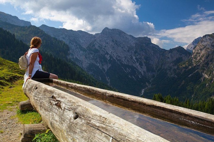 A person sitting on a wooden bench overlooking a mountainous landscape. 2