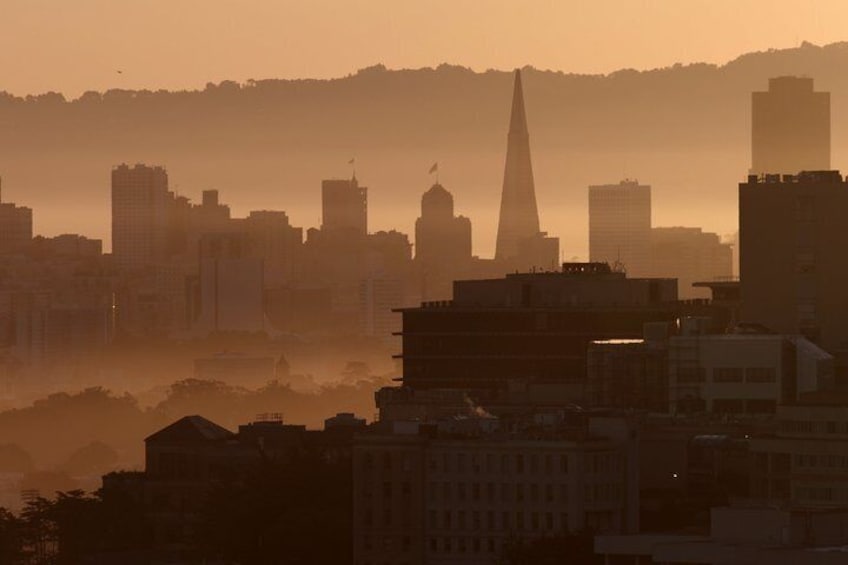 A city skyline at sunset with a prominent spire and several buildings. 1