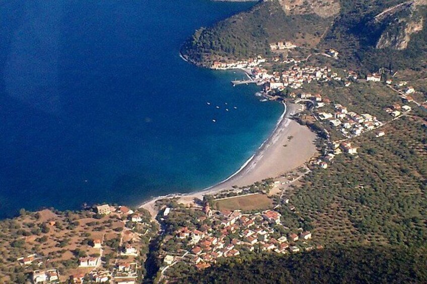 An aerial view of a coastal town with a beach, a small island, and surrounding hills. 4