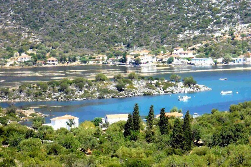 A coastal town with buildings along the shore, a clear blue sea, and a hilly landscape in the background. 5