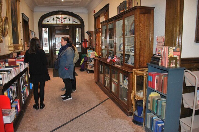 A library interior with bookshelves, a wooden cabinet, and a stained glass window. 3