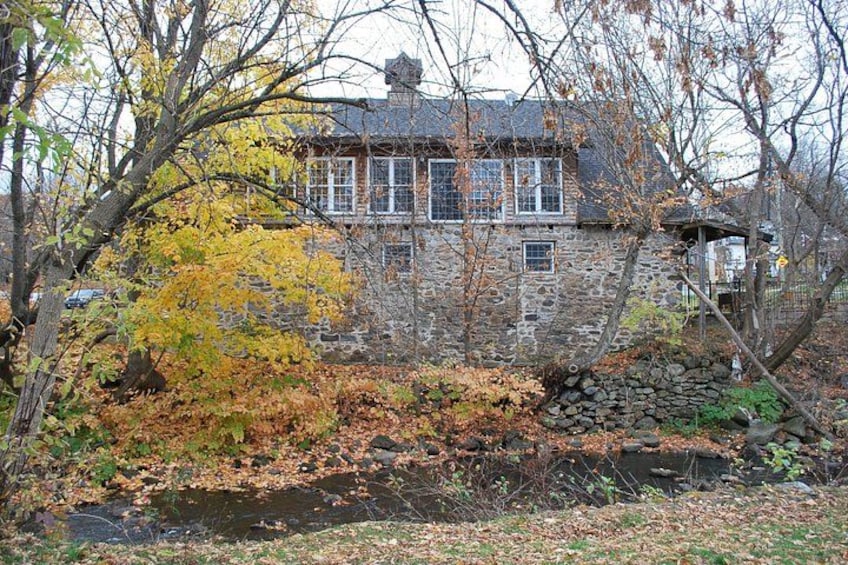 Una casa de piedra con un muro de piedra y un arroyo pequeño. 4