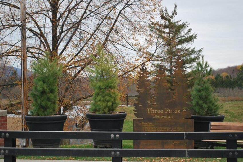 A bench with three potted plants in front of a sign that reads 'Three Piles Welcome.' 4