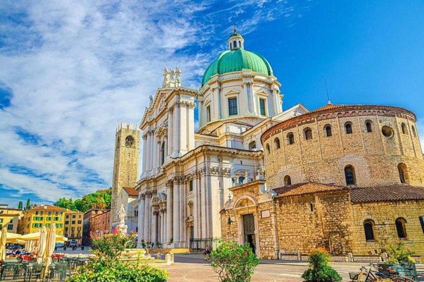 A historic church with a green dome, a bell tower, and a round building with arched windows. 3