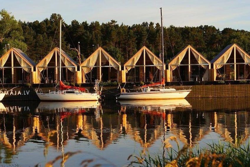 Filetta di baite in legno affacciata su un lago tranquillo, con barche ormeggiate davanti. 3