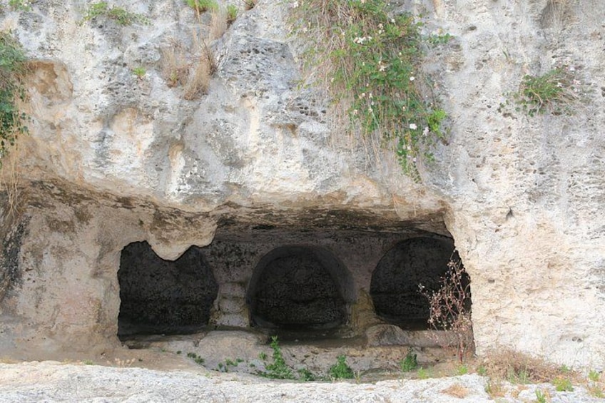L’entrée d’une grotte, avec trois ouvertures sombres. 4