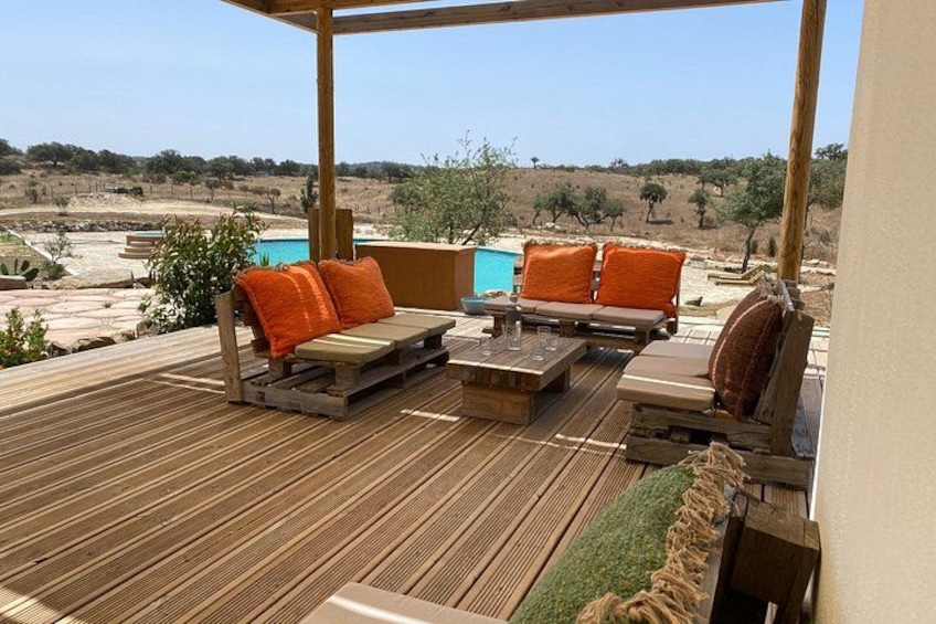 An outdoor patio with wooden furniture and a view of a pool and landscape. 4