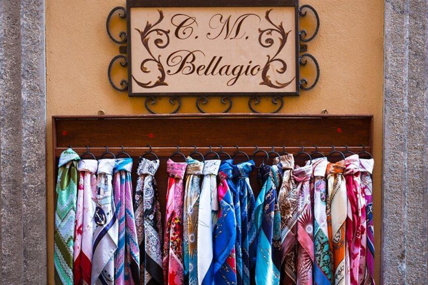 Een etalage met een bord waarop 'C. M. Bellagio' staat en een display met kleurrijke stropdassen. 2