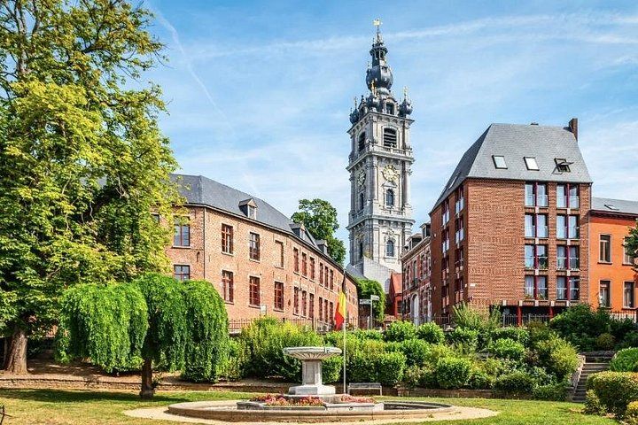 A historic building with a clock tower, surrounded by lush greenery and a fountain. 3
