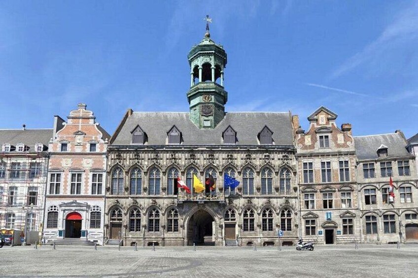 A historic building with a prominent tower and multiple flags. 1