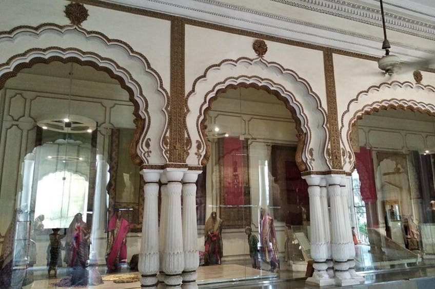 Ornate architectural columns, a glass display case, and a reflection of a person. 3