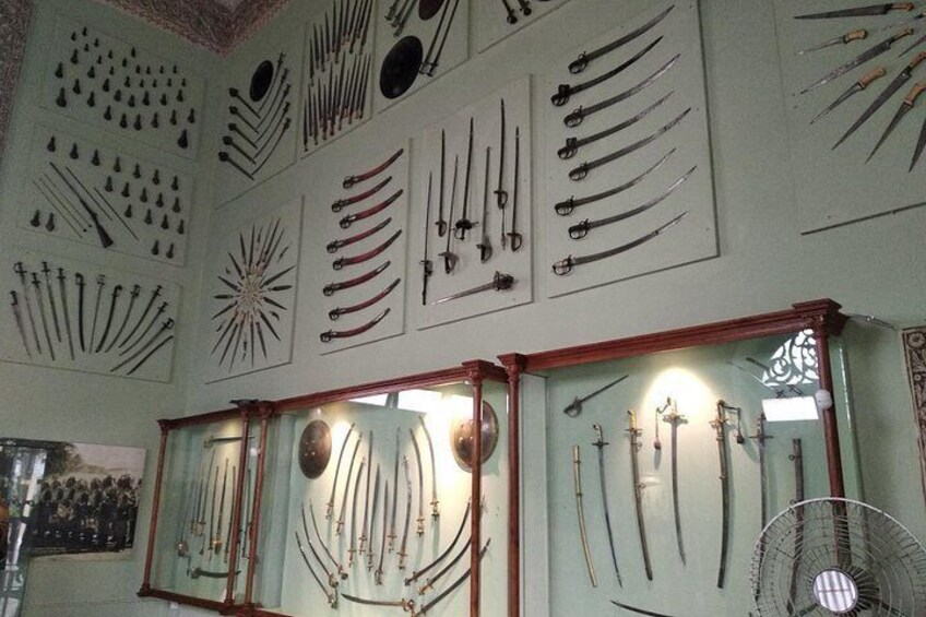 A collection of swords and knives displayed on walls and in glass cases. 5
