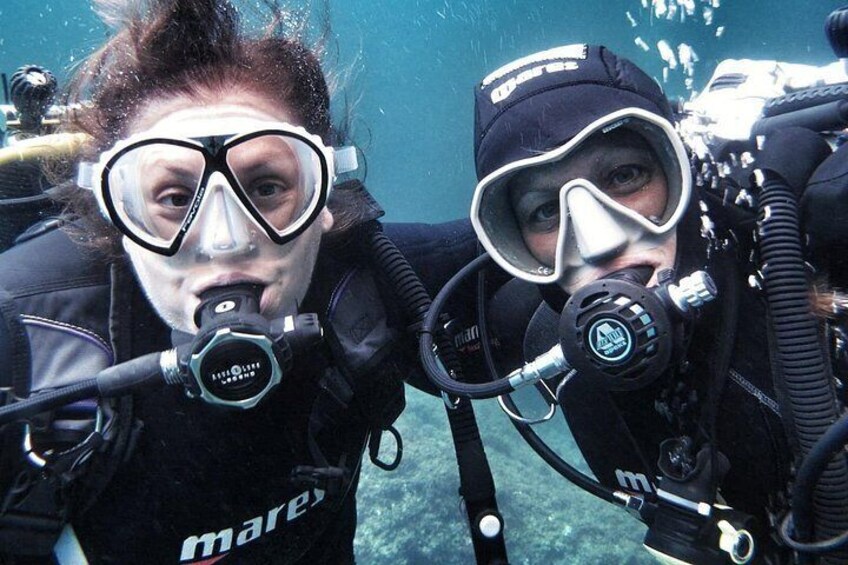 Two scuba divers with oxygen tanks and masks, underwater. 2