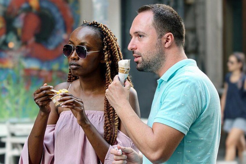 Dos personas comiendo helado en un espacio al aire libre con un mural colorido de fondo. 4