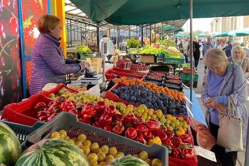 Ein belebter Markt im Freien mit verschiedenen frischen Lebensmitteln, die in Körben und Kisten präsentiert werden. 4