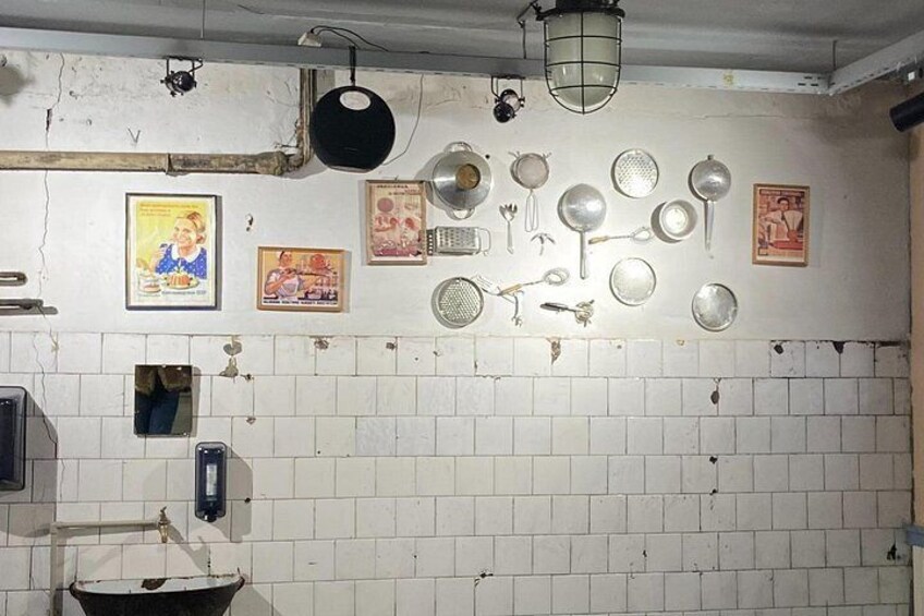Eine Küche mit weißen Fliesenwänden, verschiedenen Küchenutensilien, die an der Wand hängen, und einem Waschbecken. 5