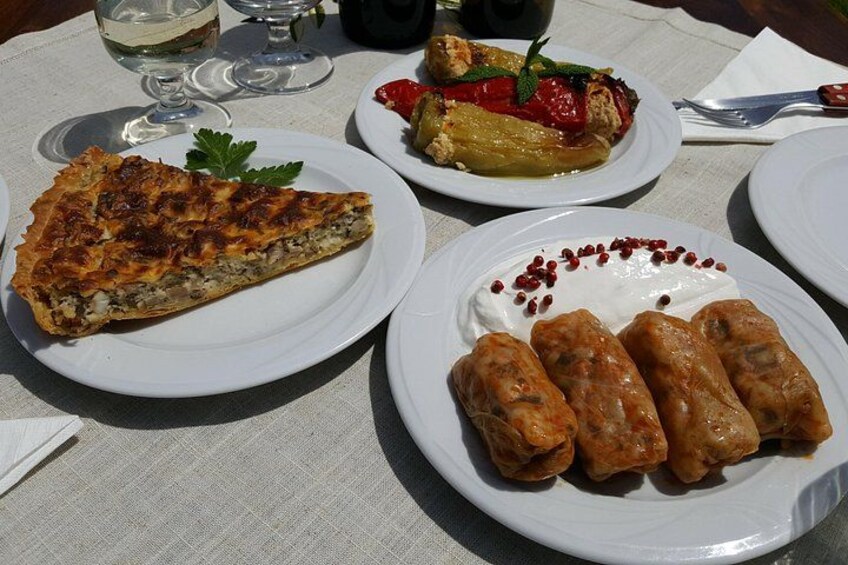 Een tafel met borden vol eten, waaronder een stuk quiche, gevulde paprika's en gevulde kooltjes. 4