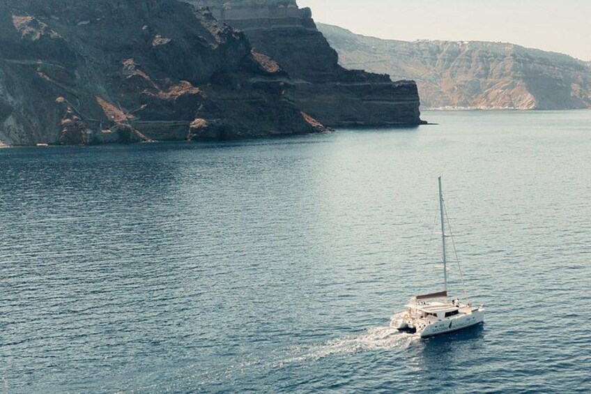 A sailboat on calm water near rocky cliffs. 5