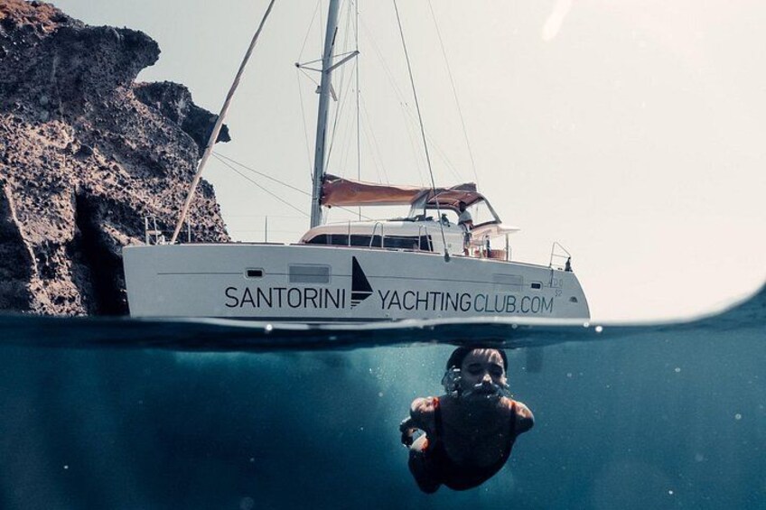 A yacht named 'Santorini Yacht Club' with a person swimming below it. 1