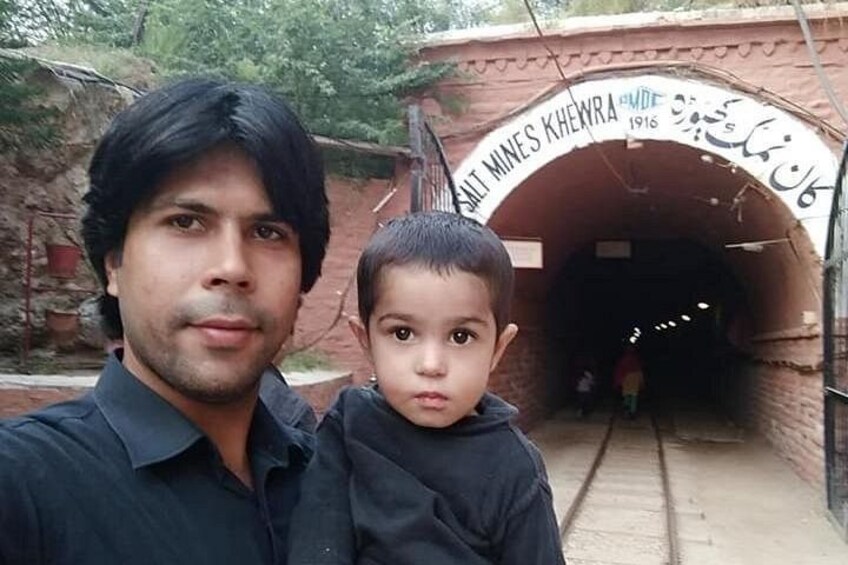 A man and a child standing in front of a tunnel with the inscription 'Salt Mines Khengra' and a date '1916'. 1