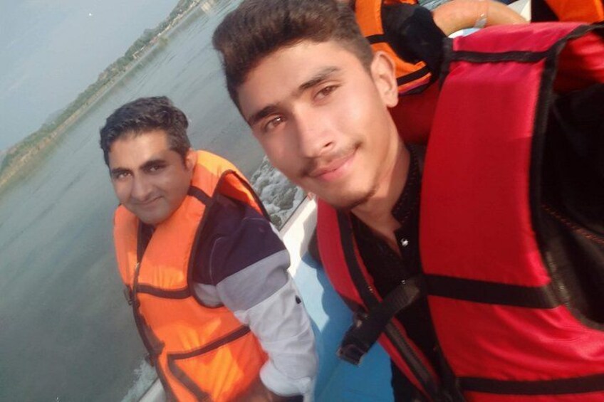 Two individuals wearing life jackets, one in orange and the other in red, on a boat. 2