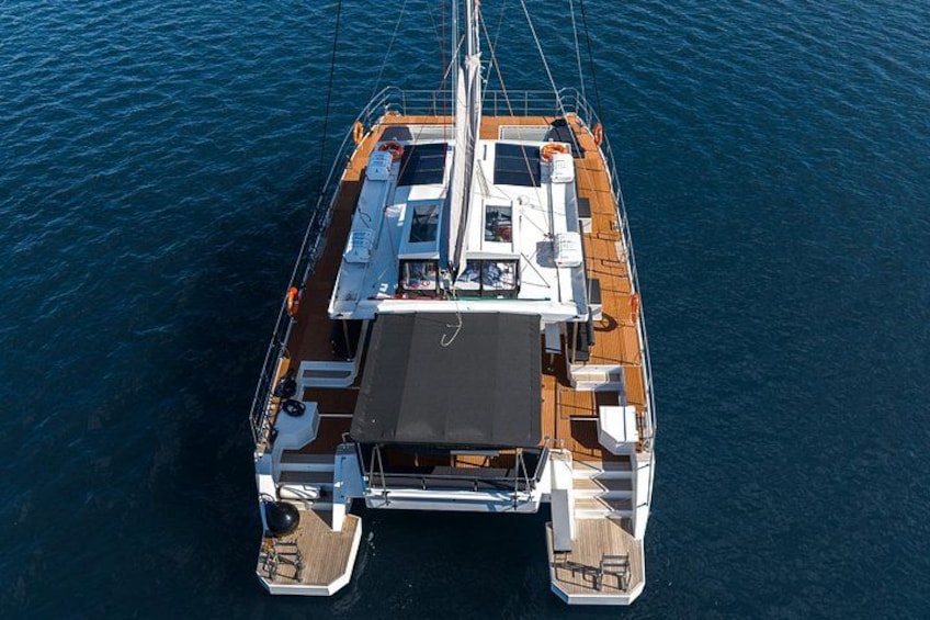 Eine große Yacht mit Holzdeck, mehreren Sitzbereichen und einem zentralen Mast. 5