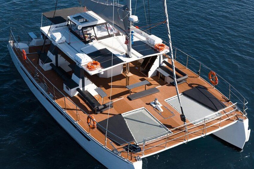 Eine große Yacht mit Holzdeck, mehreren Sitzbereichen und einer überdachten oberen Deckfläche. 1