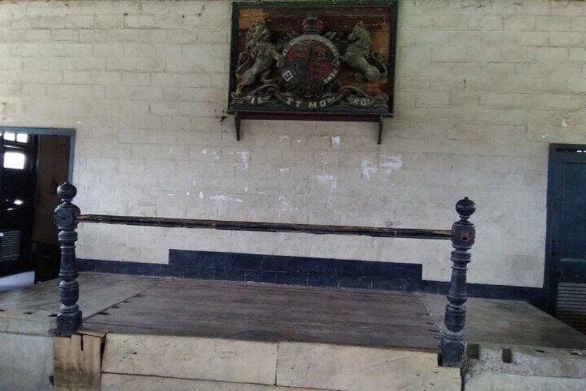 A stone bench with a metal frame, a brick wall, and a coat of arms above. 4