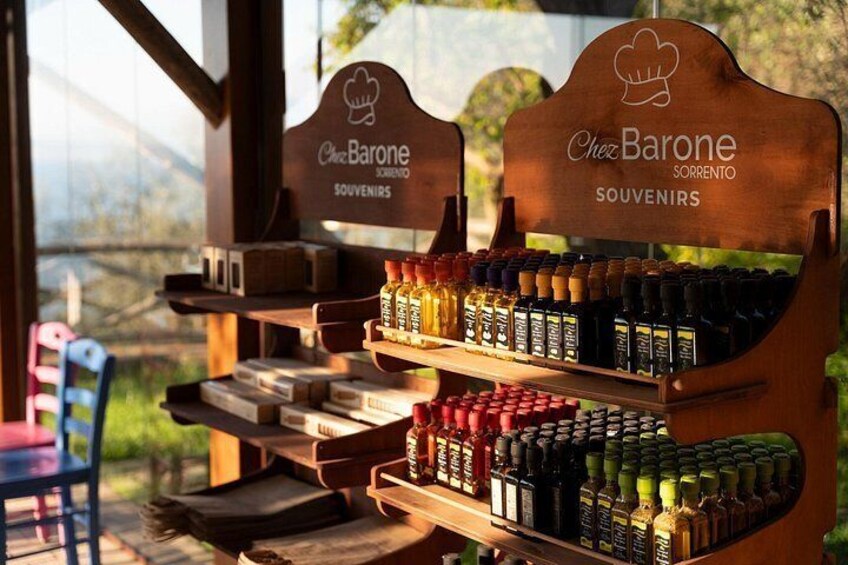 Un espositore in legno con diverse bottiglie e scatole etichettate 'Chez Barone Souvenirs'. 4