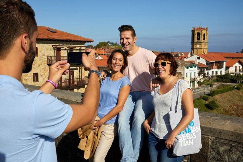 A group of people taking a photo, with a church and buildings in the background. 2