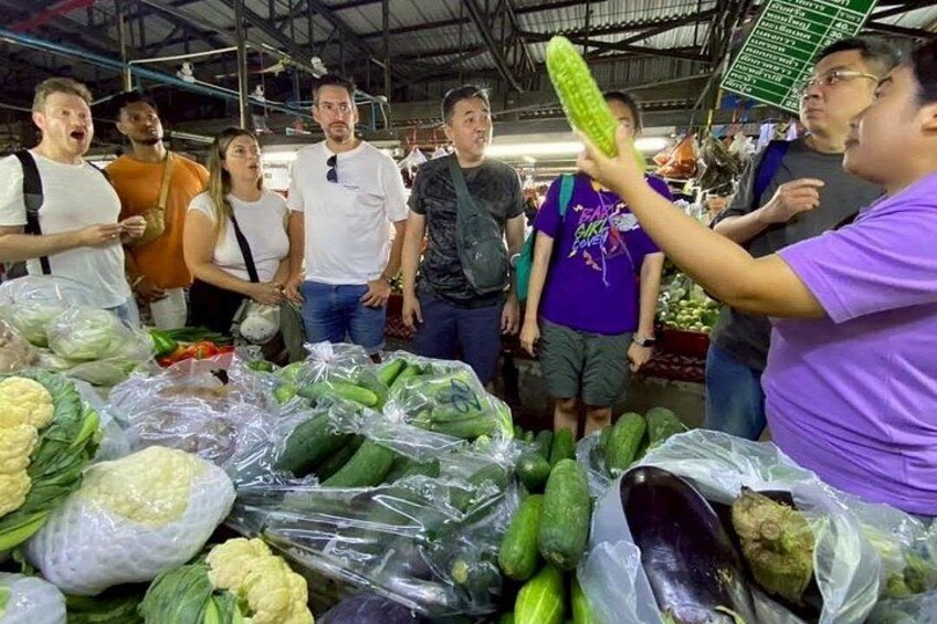 Un gruppo di persone in un mercato con diverse verdure esposte. 5