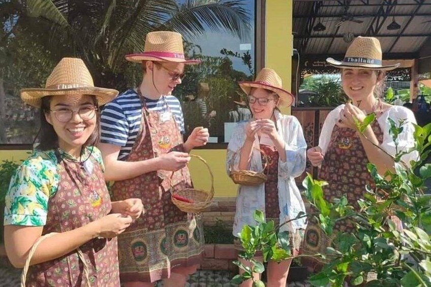 Quattro persone con cappelli e grembiuli, che tengono cesti, in piedi di fronte a un edificio giallo con una palma sullo sfondo. 2