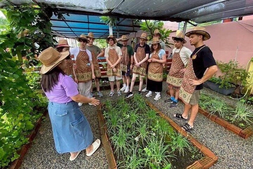 Un gruppo di persone con grembiuli e cappelli in un giardino con aiuole rialzate. 5