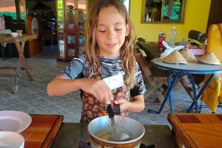 A child stirring a pot on a stove in a kitchen. 3