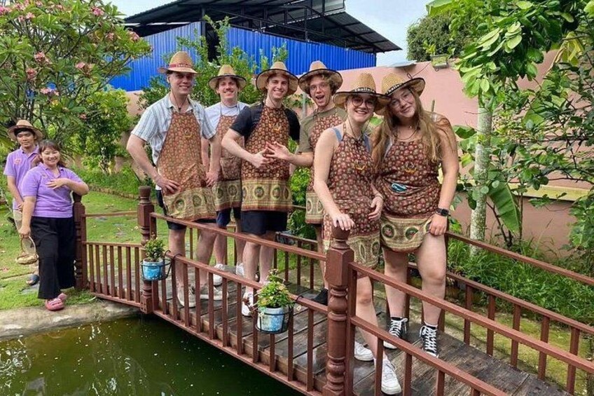 A group of people on a wooden bridge over a water body, wearing hats and aprons. 4