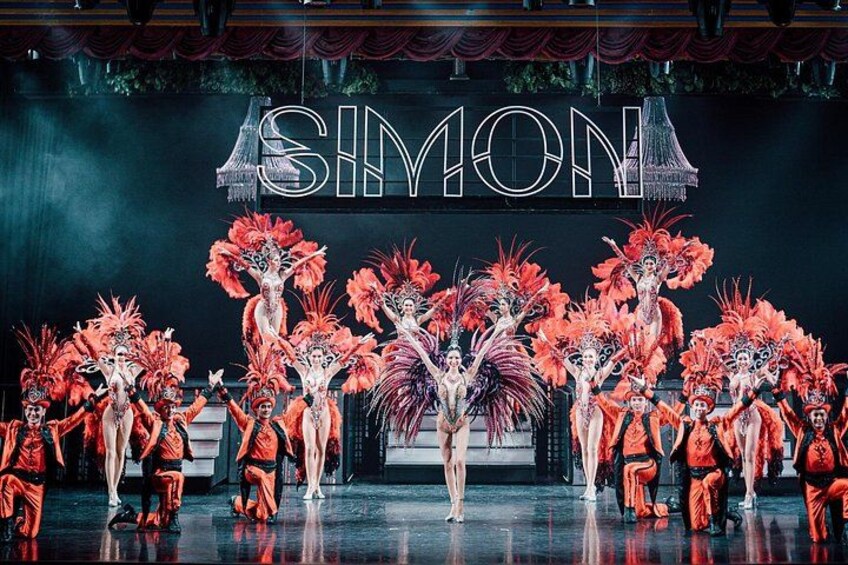 A stage with performers in elaborate costumes and a backdrop with the word 'SIMON'. 5