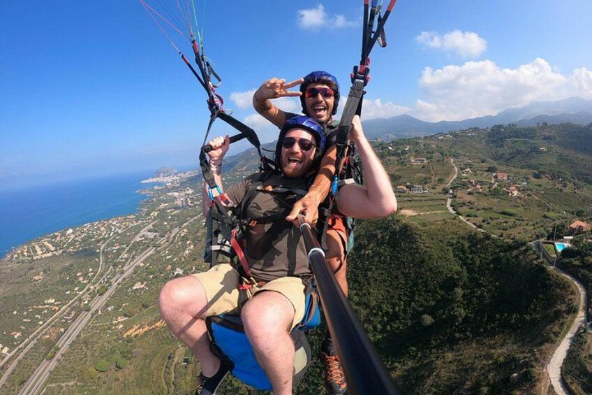 En person paraglider over et smukt landskab med kystlinje og en snoet vej. 5