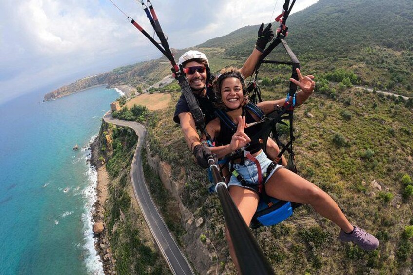 En person paraglider over et kystlandskab med en vej og klipper. 2