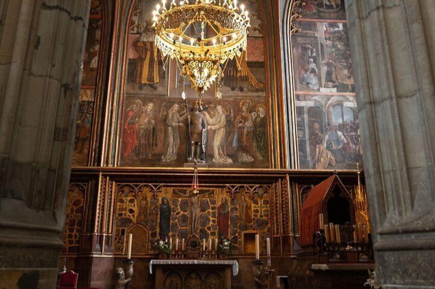 A church interior with a large chandelier, detailed woodwork, and religious paintings. 5