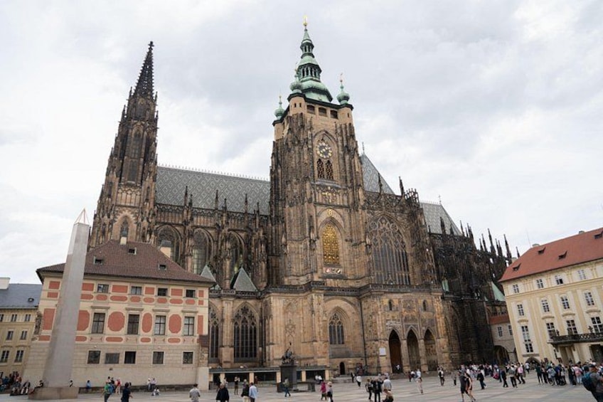 Une cathédrale historique, dotée de deux flèches jumelles, d’une grande horloge et d’une foule au premier plan. 1