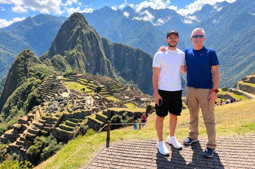 Dos personas de pie en un sendero, con las ruinas de Machu Picchu al fondo. 2