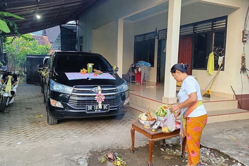 A black van parked outside a building, a woman standing next to a table with food items, and a motorcycle in the background. 5