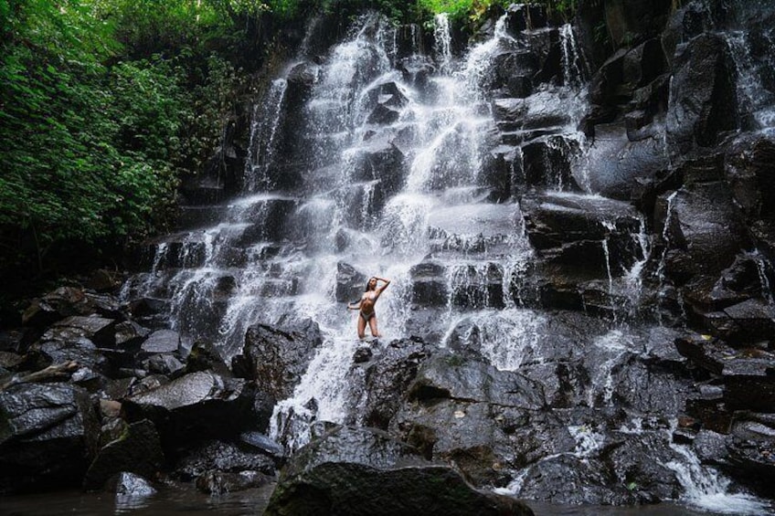 A waterfall cascading over rocks with a person standing on the rocks. 4