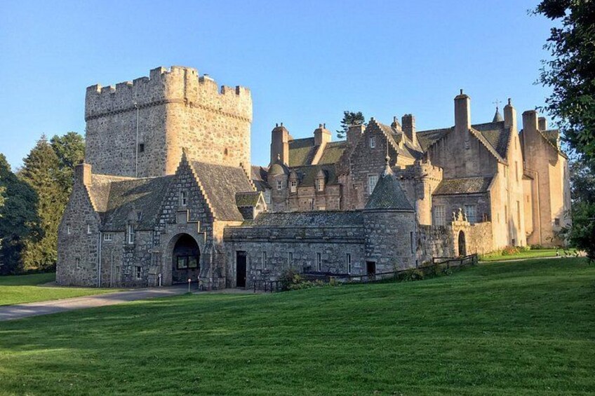 A historic stone castle with a prominent tower, surrounded by a well-maintained lawn. 2