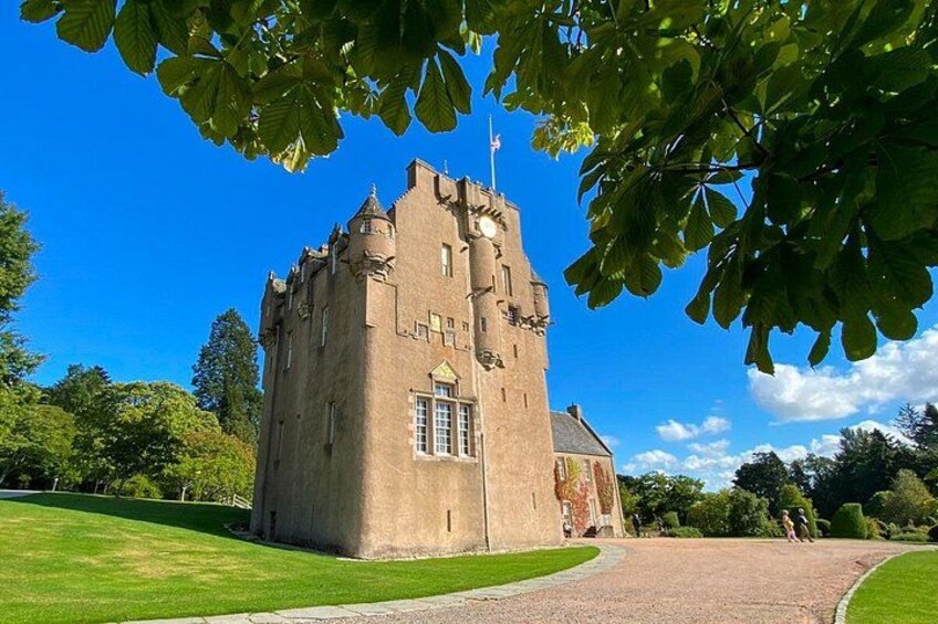 A castle with a tower, surrounded by a well-maintained lawn and trees. 2