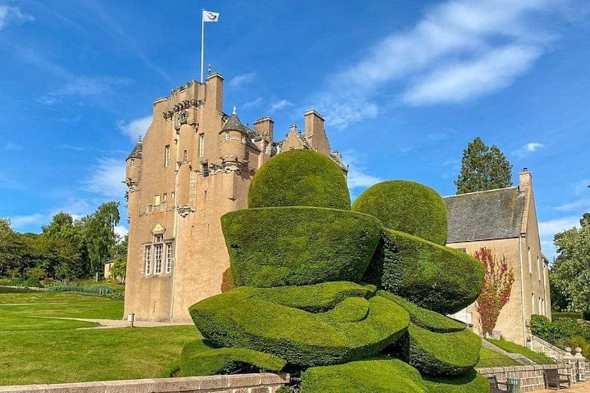 Un château doté d’une pelouse parfaitement entretenue et d’une grande sculpture végétale réalisée à partir d’un arbuste taillé. 5