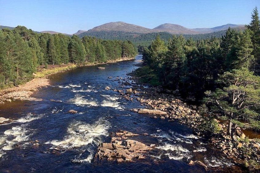 Une rivière qui traverse une vallée boisée, avec des montagnes en arrière-plan. 2